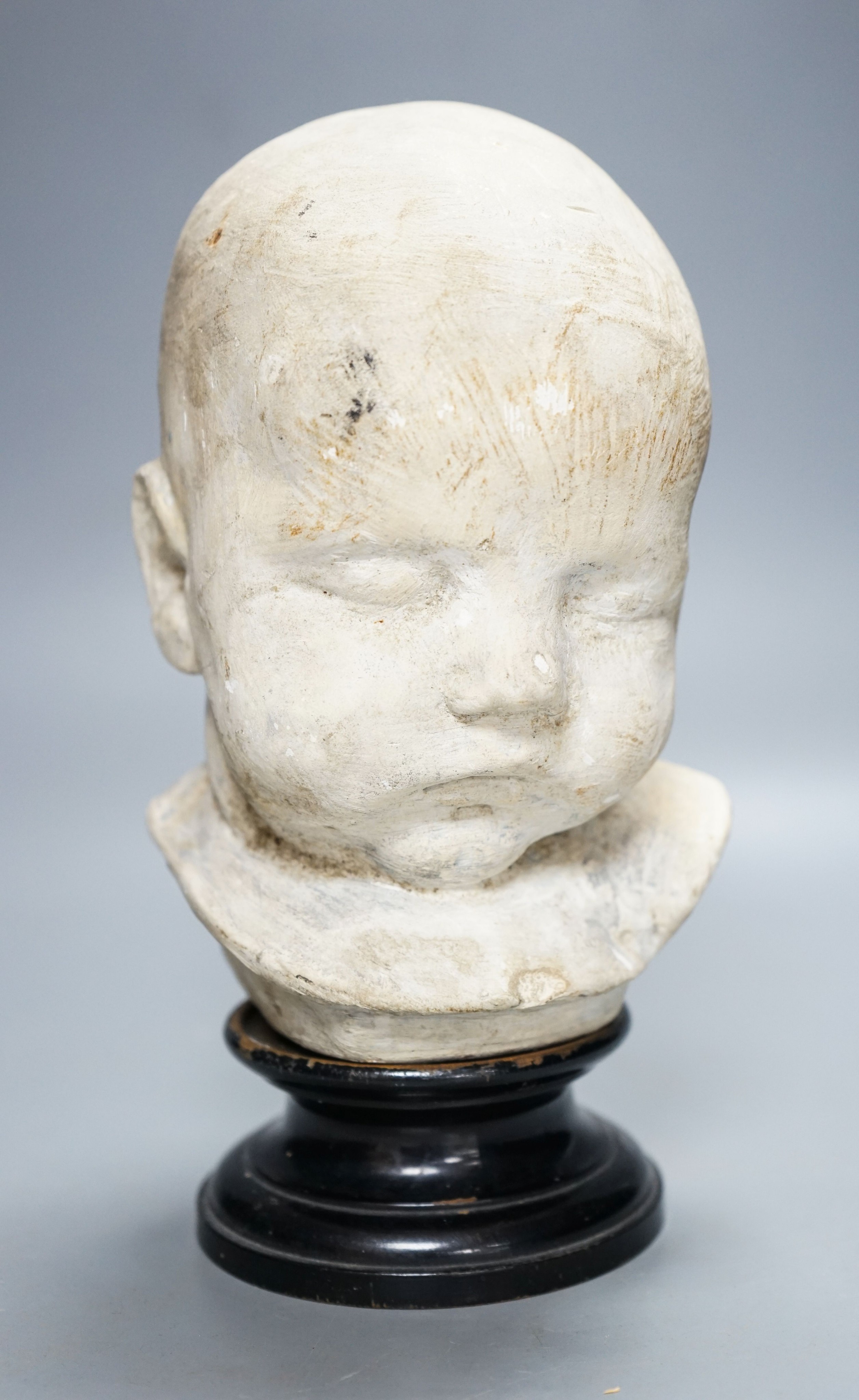 A 19th century memento mori plaster bust of an infant, on ebonised socle 22cm